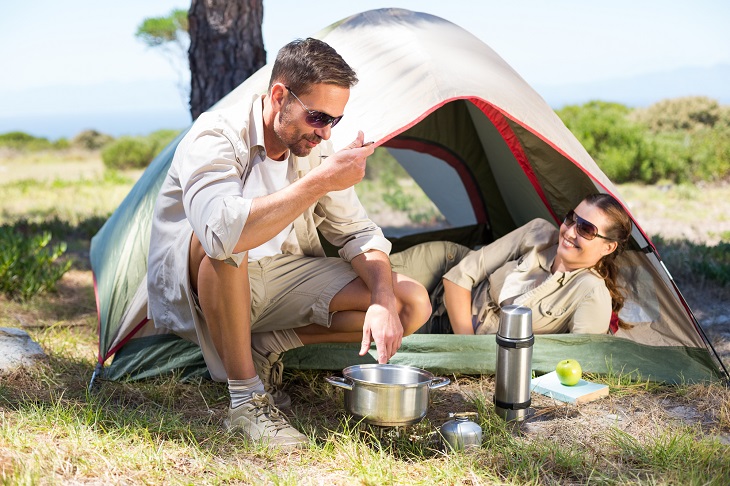 Outdoorsy couple cooking on camping stove