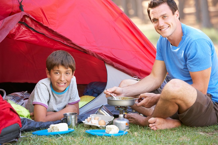 father and son camping cooking breakfast on camp stove