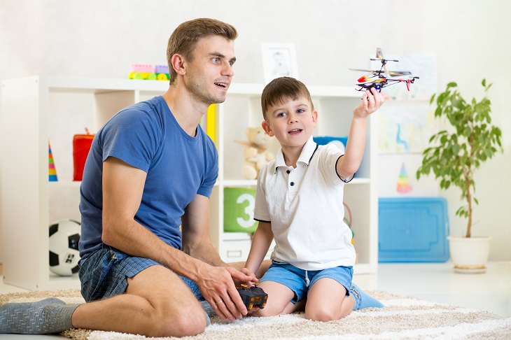 Father and his son play with RC helicopter toy 