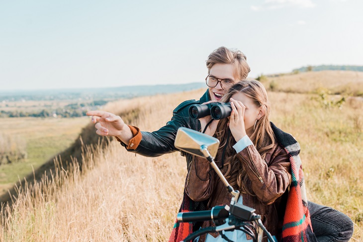 how to use binoculars guide - couple looking at scenery through bincoculars