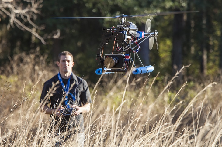 man flying RC helicopter in field